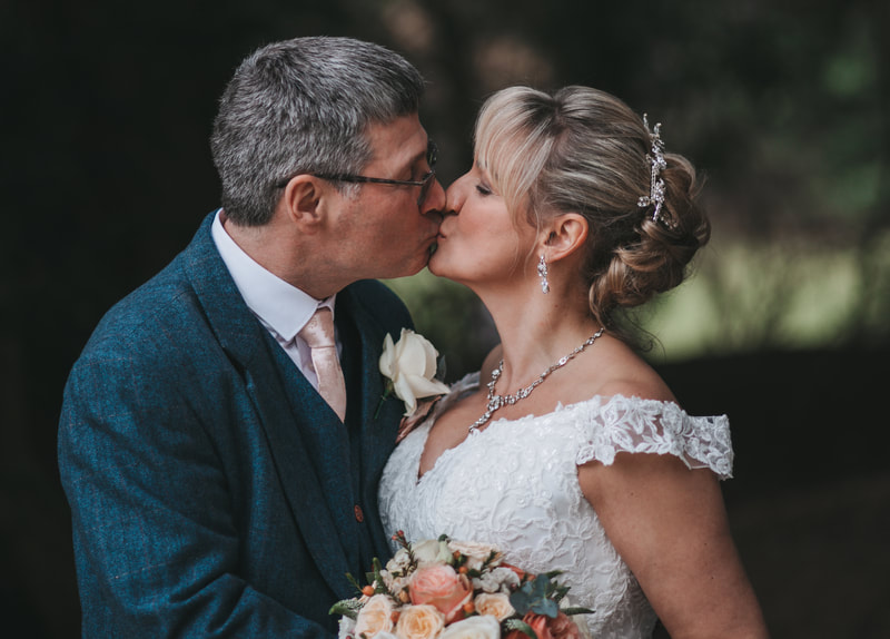 Stunning couple embracing with a kiss on their wedding day with the beautiful back drop of Holmewood Hall Cambridgeshire  Cambridgeshire Essex Bride and groom happy wedding candid wedding Holmewood hall Gayers Park Sopwell House St Albans Hunton Park Huntingdon 