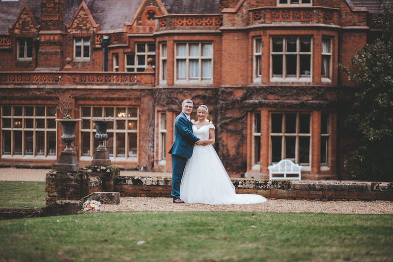 Stunning couple embracing with a kiss on their wedding day with the beautiful back drop of Holmewood Hall Cambridgeshire 